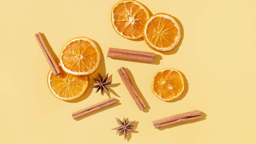 cinnamon sticks and orange slices on an orange background.
