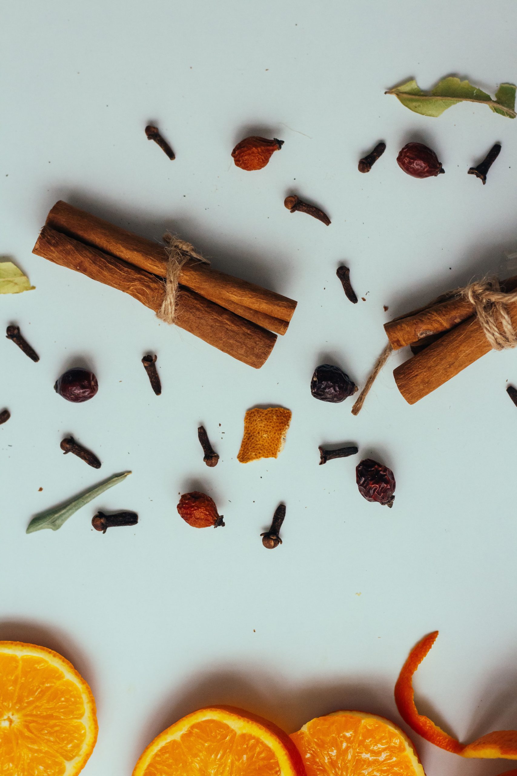 Warm vs. Fresh Fragrances: Which Is Right for Your Home? A flat lay of cinnamon sticks, cloves, and orange slices, perfect for culinary themes.